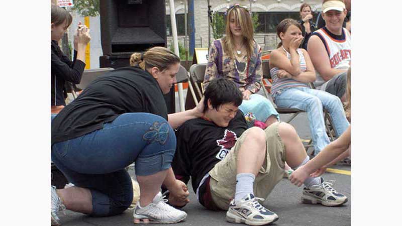 Stage Hypnosis Show 1, Hypnotist Hamilton, Teenage boy giving birth to a baby being helped by a hypnotised woman who thinks she is a doctor, guests laughing the background. Taken in Hamilton Ontario